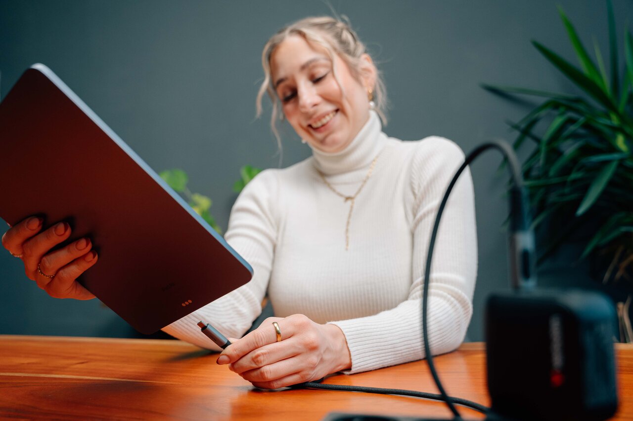 mujer enchufando un cable a un ipad, conectado a un cargador portátil