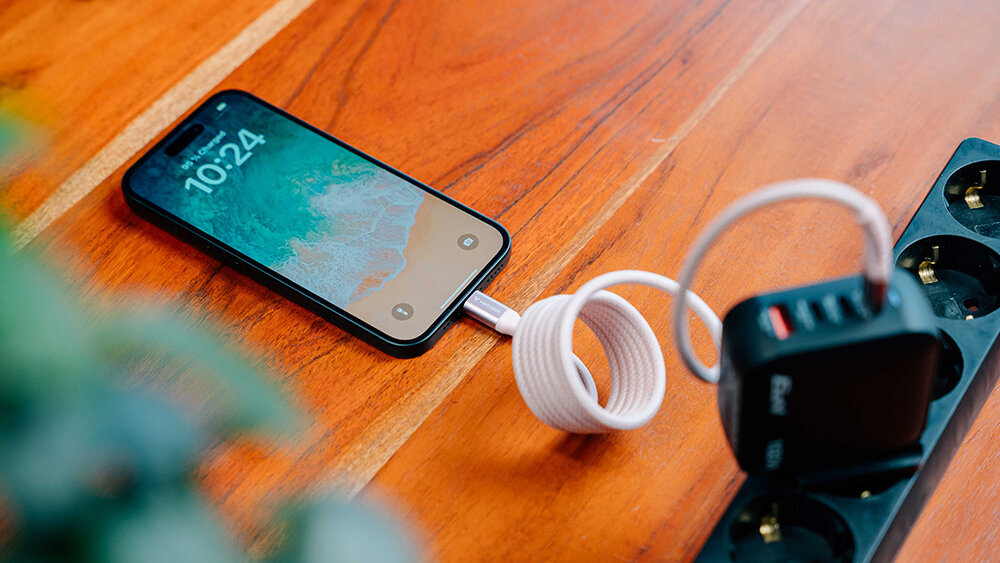 Pink USB-C cable charging an iPhone from a multi-port plug