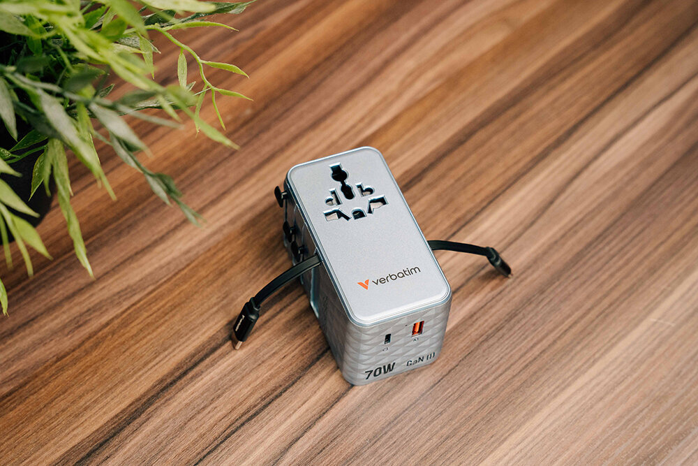 Travel adapter with 2 built in cables on a tabletop with a plant