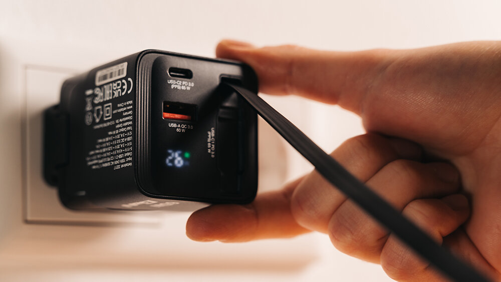 Hand plugging a charger into a socket.