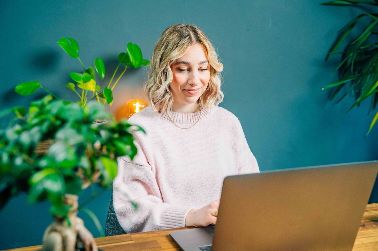 Žena s laptopom i biljkom s osmijehom na licu