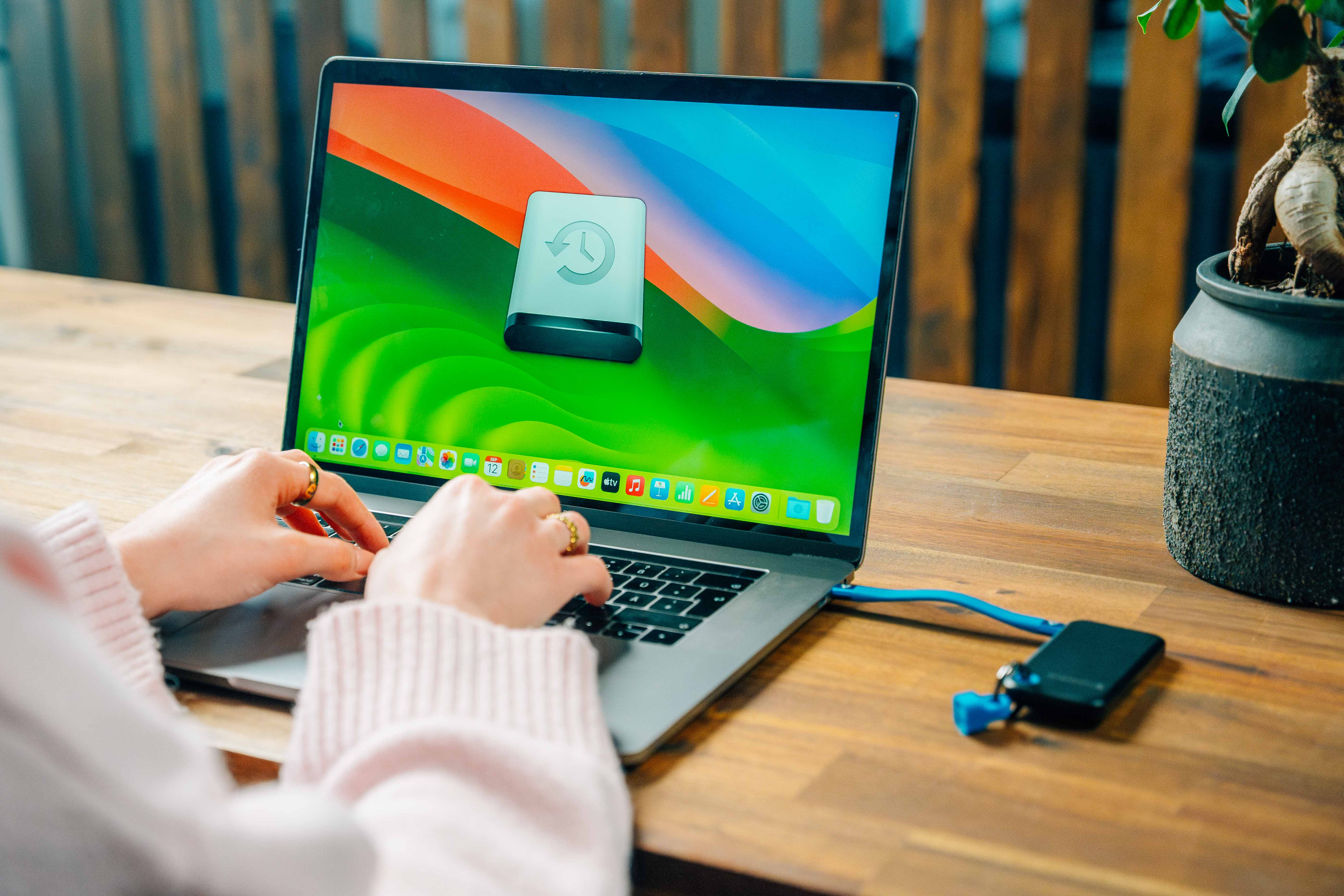 En bärbar dator på ett skrivbord där säkerhetskopieringsprogrammet visas, med en bärbar SSD ansluten